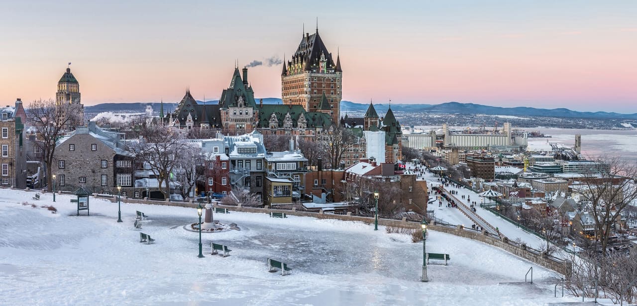 Snow-covered Old Quebec and the Château Frontenac at dusk after a day of freezing rain, with the St. Lawrence beyond.