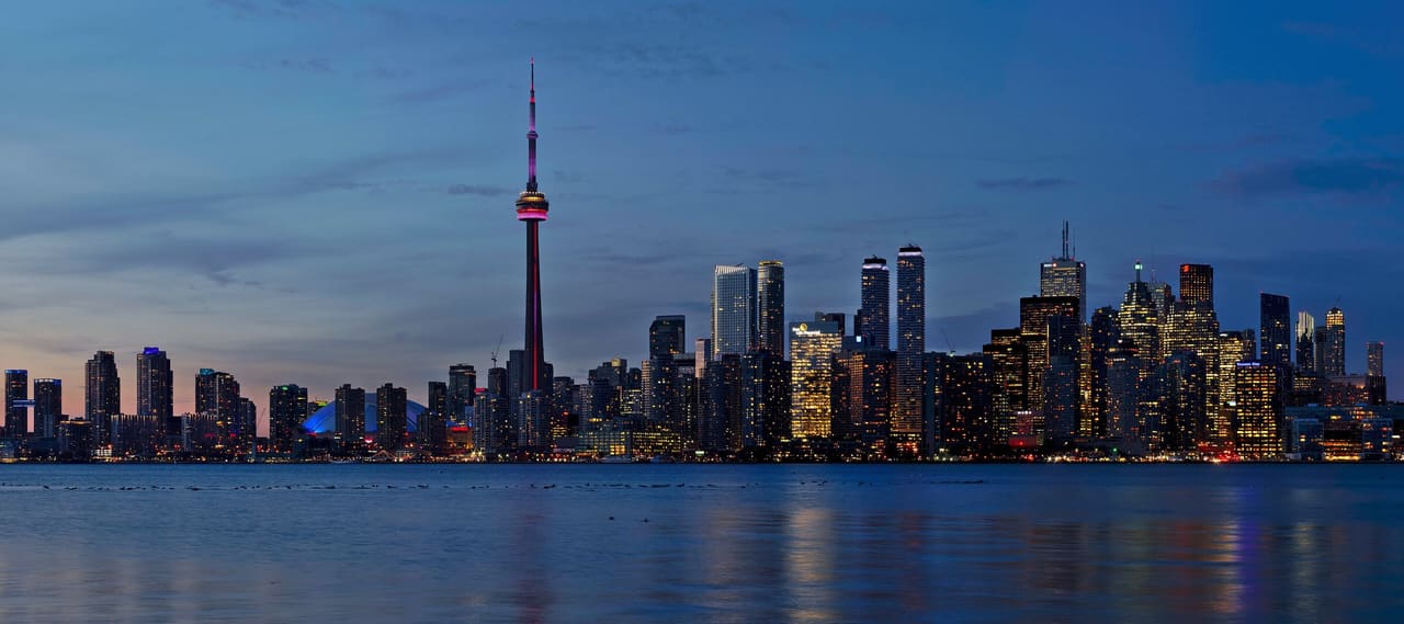 The Toronto skyline and CN Tower lit up at dusk across the harbour, seen from Snake Island on the Toronto Islands.